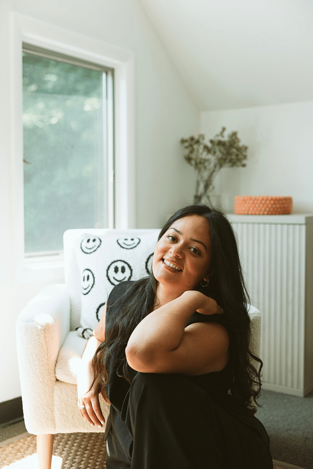 Portrait of Erika Valencia, holistic psychotherapist at Mindfully Life, smiling warmly in a bright and serene therapy space