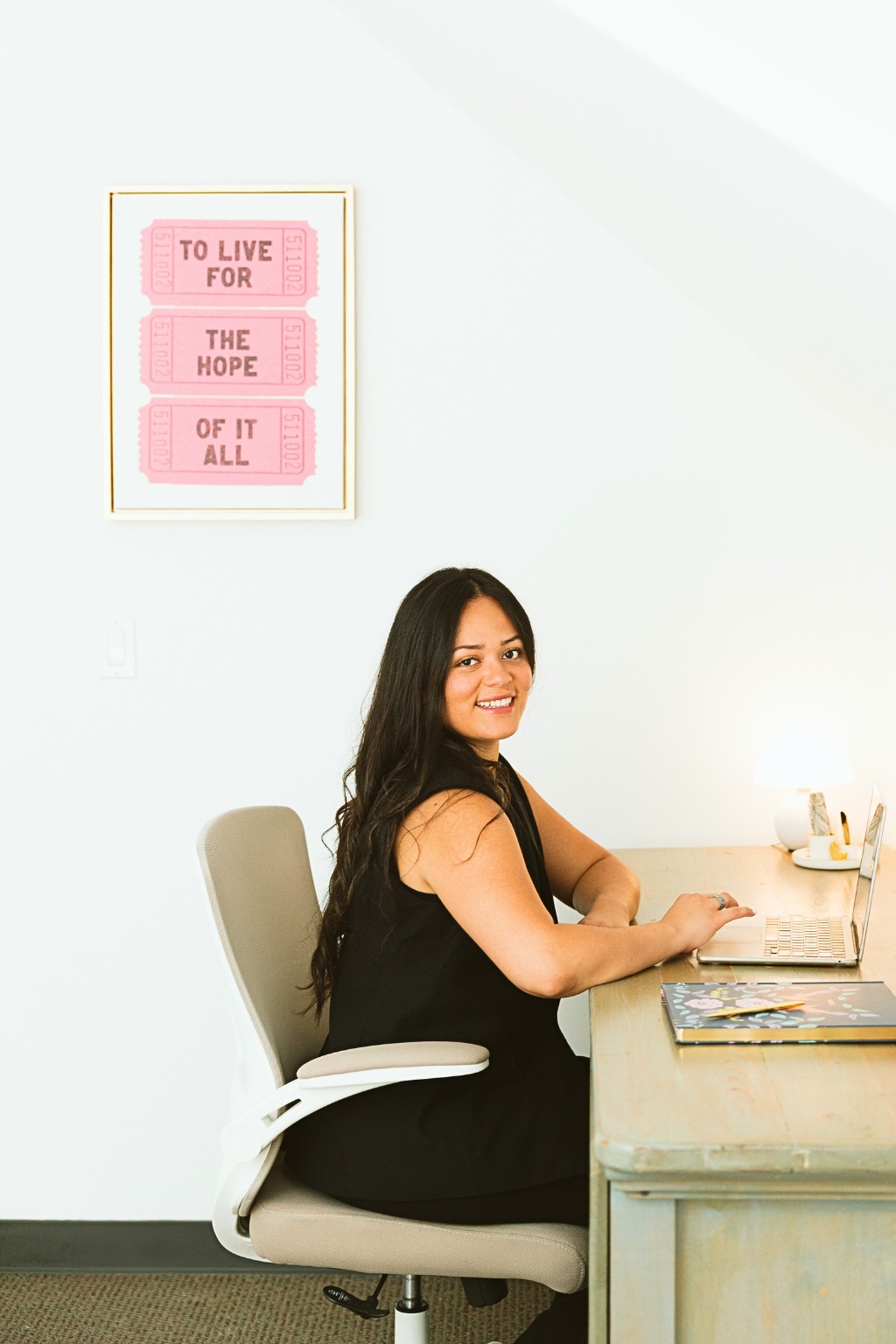 Erika Valencia, holistic psychotherapist, seated at her desk smiling toward the camera, creating a warm and welcoming contact environment at Mindfully Life